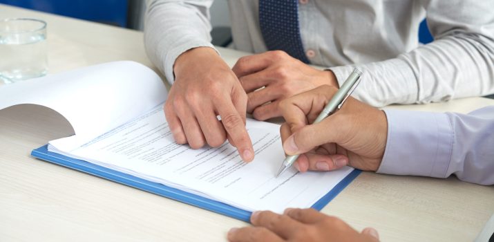 Businessman showing his partner where to sign the contract